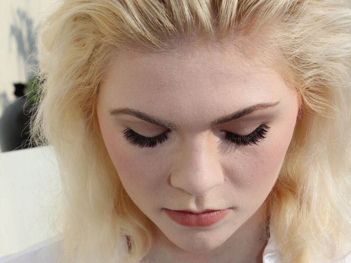 Blond pale skinned woman wearing volume eyelash extensions looking down