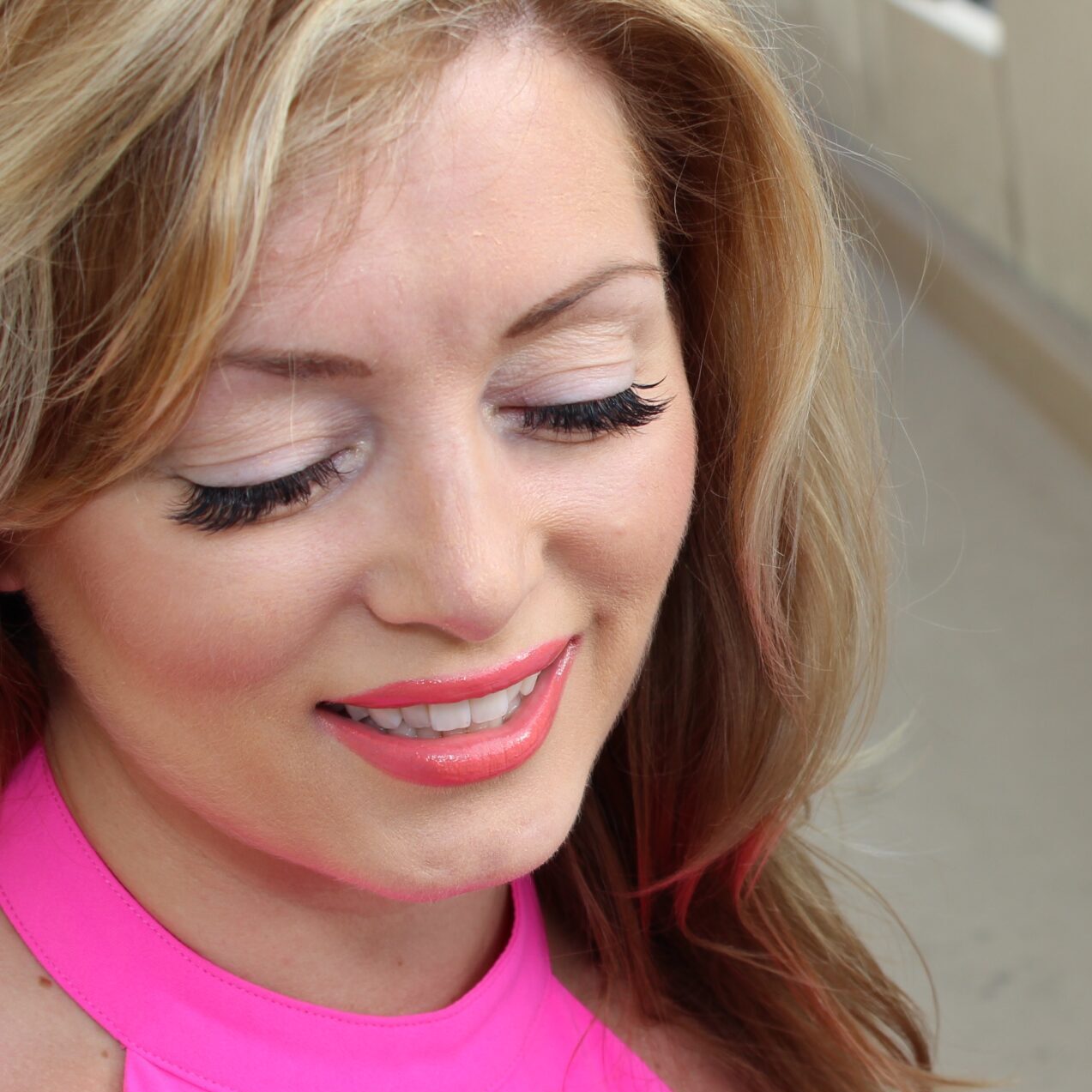 Blonde woman wearing eyelash extensions smiling. 